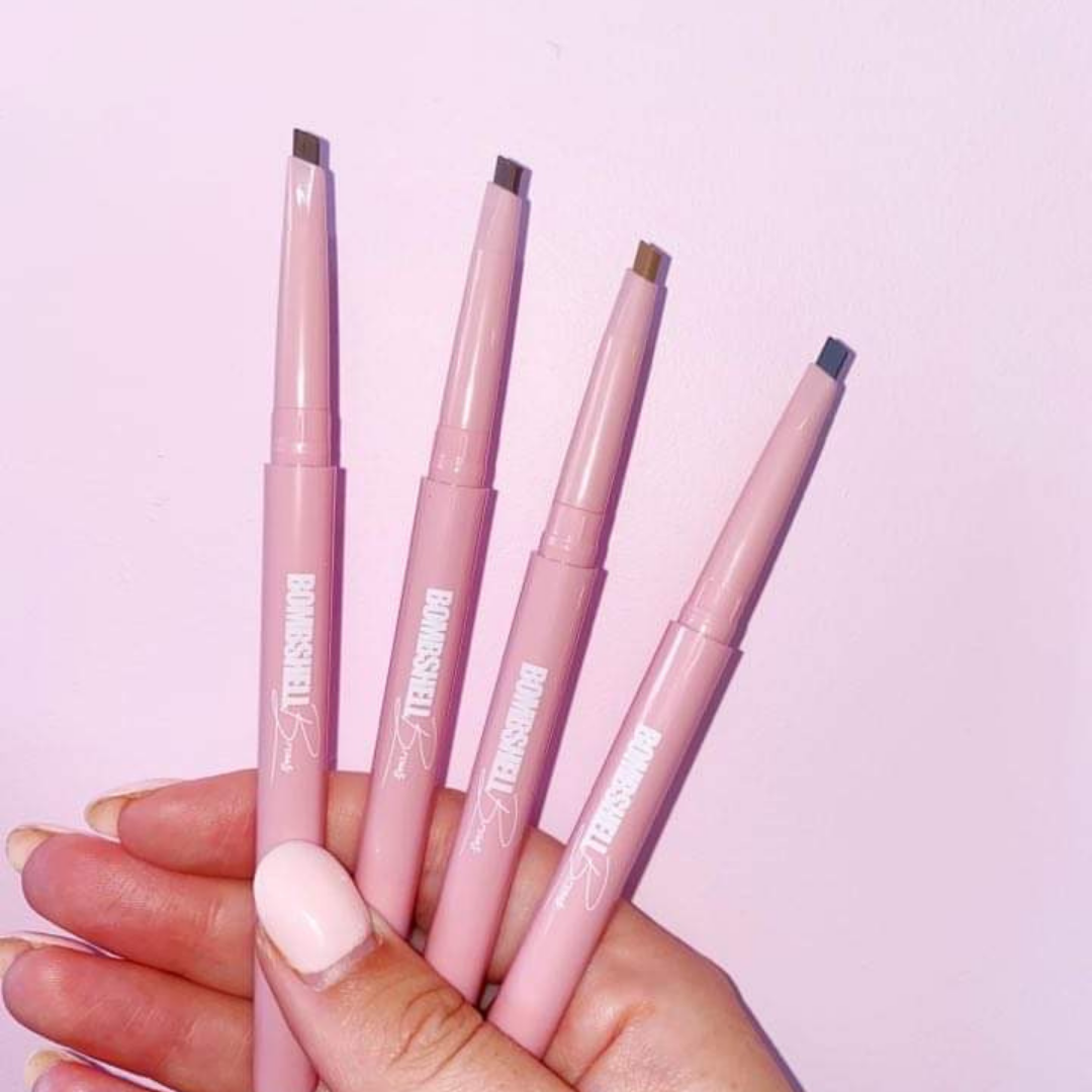 Four beauty travel essentials pink eyebrow pencils held in hand for on-the-go beauty.
