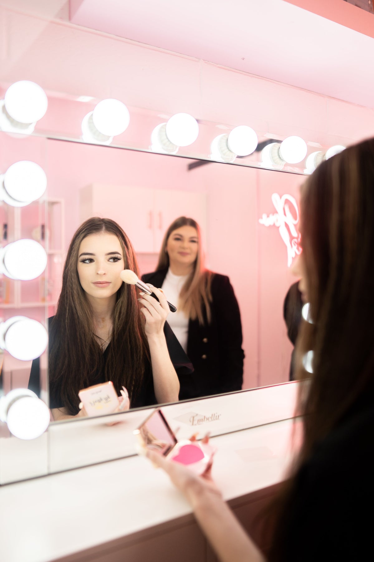 Woman applying makeup in a beauty salon, showcasing a recession proof beauty business.