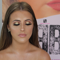 Makeup Masterclass featuring a model with stunning glam makeup showcasing gold eye shadow and flawless skin.